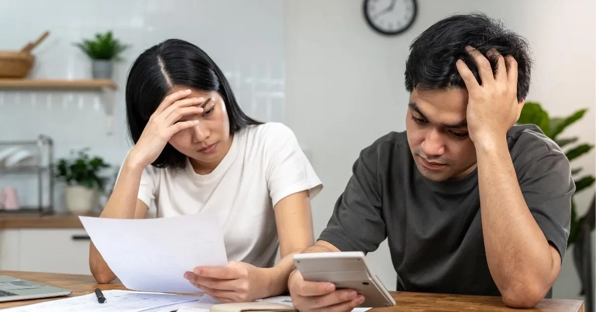 Couple sitting side by side with calculator and papers