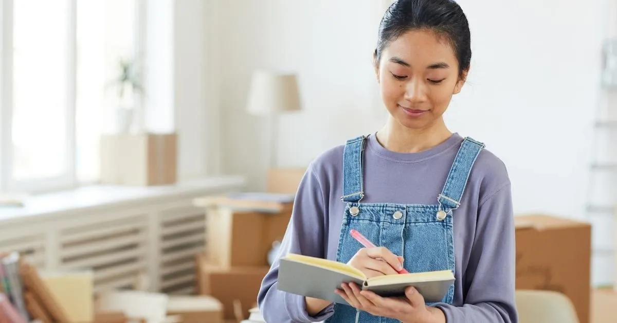 Woman writing on a notebook in overalls