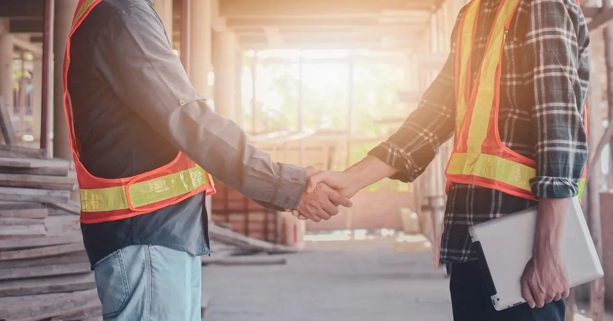 Shaking hands of 2 men in orange vests